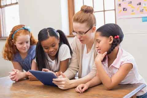 Teacher-and-pupils-looking-at-tablet-computer-at-the-elementary-school